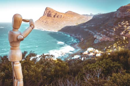 Wooden Human Manikin posing on a cliff with a beautiful misty sea from a view point at Cape Point Nature Reserve, Cape Point, Cape Town, South Africa